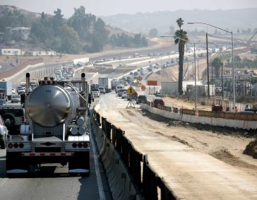 Congested freeway with construction zone and traffic, air pollution concerns.