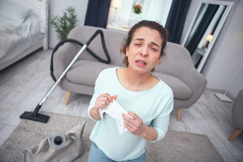 woman sneezing in dusty house