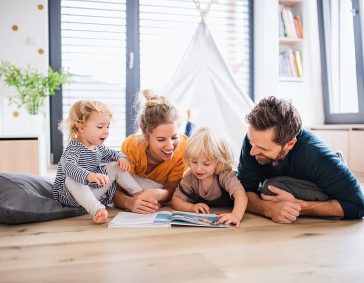 Parents and children reading together in a cozy living room, promoting family bonding and healthy indoor air quality.