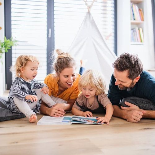 Parents and children reading together in a cozy living room, promoting family bonding and healthy indoor air quality.