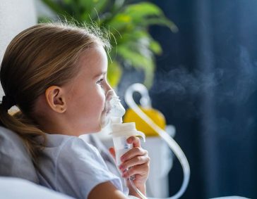 Child using an inhaler for asthma relief in a cozy home setting.